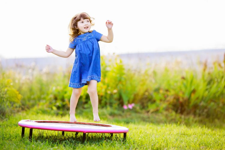 Child jumping on trampoline in a field