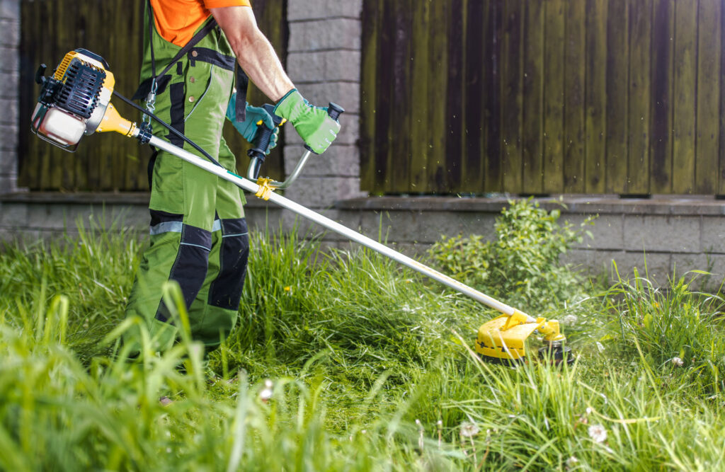 man using a gas powered string trimmer on his lawn