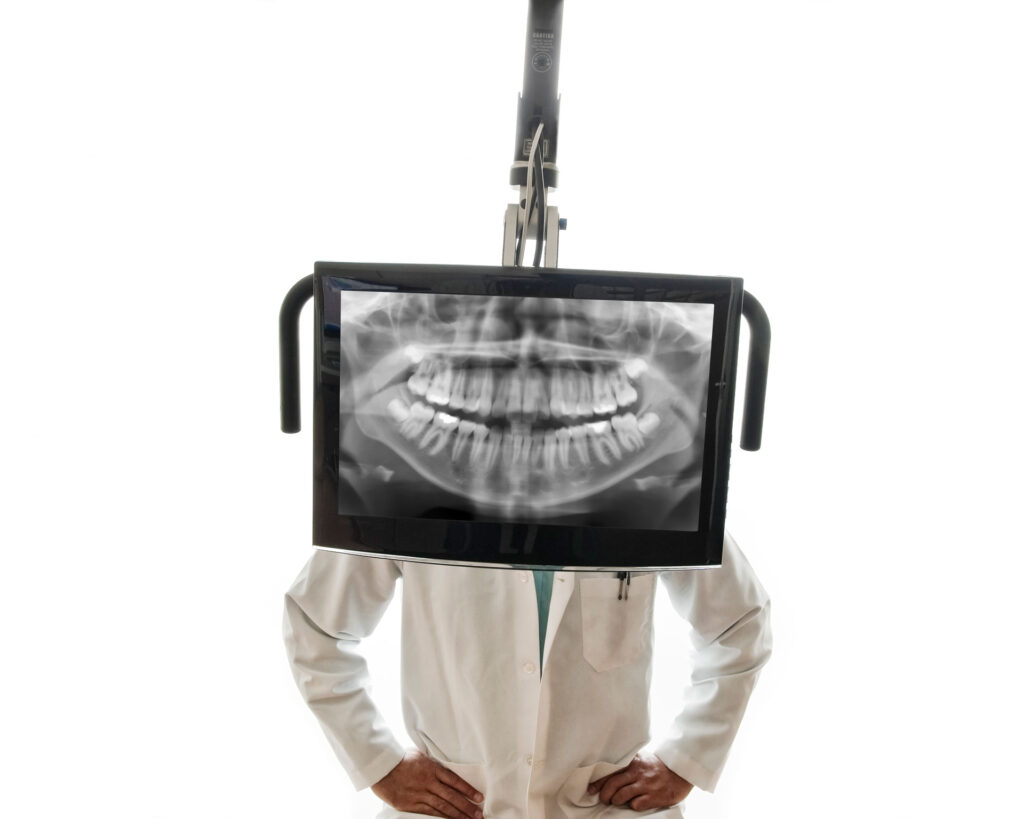 dentist standing behind dental x-ray screen